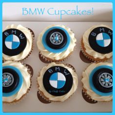 four cupcakes with bmw emblem on them are in a white and blue box