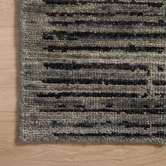 a gray rug with black and white stripes on it, sitting on a wooden floor