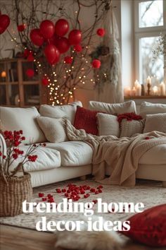 a living room filled with lots of white furniture and red balloons hanging from the ceiling