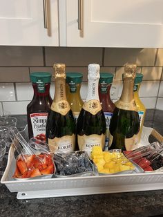 several bottles of wine, fruit and condiments on a kitchen counter