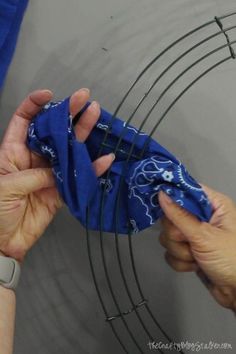 two hands are holding a blue cloth over a wire rack