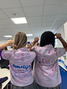 two women in pink shirts standing next to each other with their hands on their backs