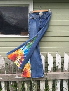 a pair of jeans hanging on the side of a wooden fence next to a window