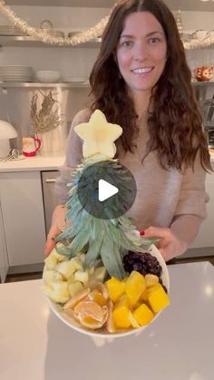 a woman holding a bowl full of fruit and vegetables