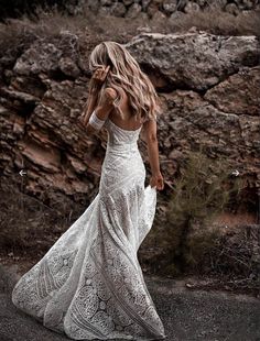 a woman in a white dress walking down the road with her back to the camera