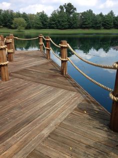 a wooden dock with ropes and water in the background