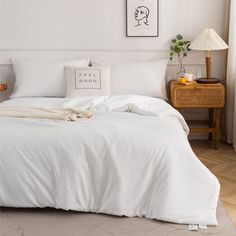 a bed with white sheets and pillows on top of it next to a lamp in a room