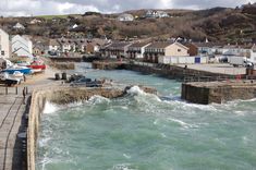 the water is choppy and green in this small town by the sea side with houses on the hill behind it