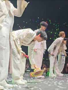 a group of young men standing on top of a stage with confetti all around them