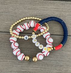 three bracelets with baseball beads and gold balls on wooden background, close up view