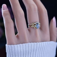 a woman's hand with a ring on top of her finger, wearing a white sweater