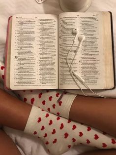 an open book on top of a bed next to a cup of coffee and headphones