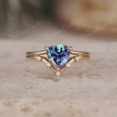 a blue heart shaped ring with two diamonds on the sides and an arrow design in the middle