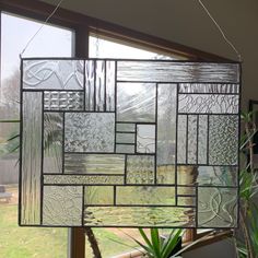 a stained glass window hanging from the ceiling next to a potted plant in front of a window