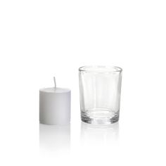 an empty glass with a white candle on the top and one in the middle next to it