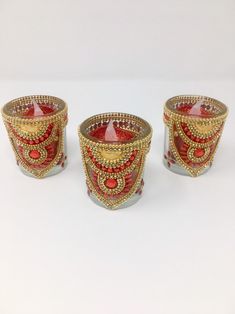 three red and gold decorated glass candlesticks