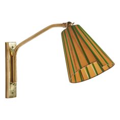 a wall light with a striped shade on the lamp is shown in gold and green