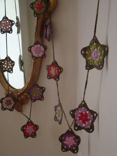 some crocheted flowers are hanging from a wall next to a mirror with a wooden frame