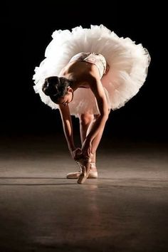 a ballerina bending down to pick up her shoe