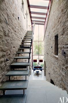 the stairs lead up to the second floor in this modern house with stone walls and steel railings