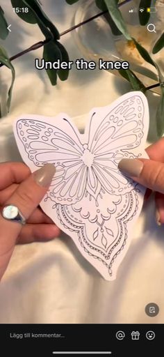 someone is cutting out a paper butterfly on a sheet of white fabric with the words under the knee