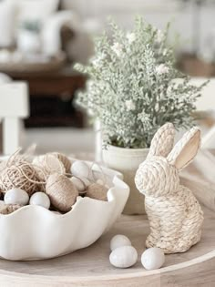 a white bowl filled with eggs and some bunny figurines on top of a table