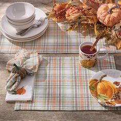 a table set for thanksgiving with plates, cups and napkins on the placemat