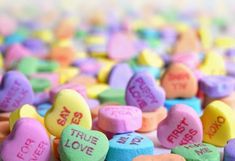 many conversation hearts with the words true love written on them in different colors and shapes