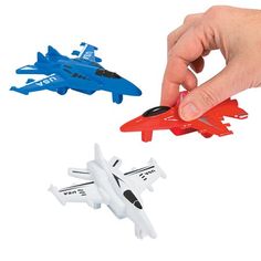 a hand is pointing at three toy airplanes