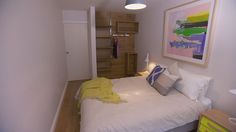 a bedroom with white bedding and wooden shelves on either side of the bed is an open closet