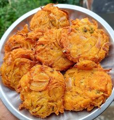 some food is on a metal plate in the middle of someone's hand and it looks like they are fried