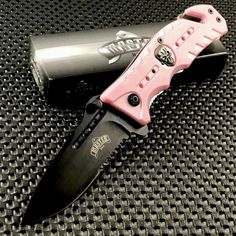 a pink and black knife sitting on top of a metal box next to a lighter