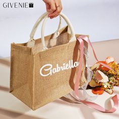 a person holding a shopping bag with the word gabrillo on it and flowers