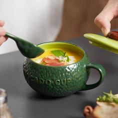 a person spooning soup into a green bowl