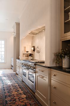 a kitchen with white cabinets and an ornate rug on the floor in front of it