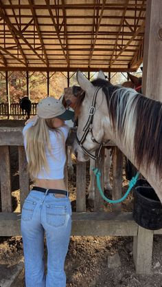 a woman standing next to a brown and white horse