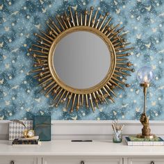 a mirror sitting on top of a white dresser next to a blue and gold wall