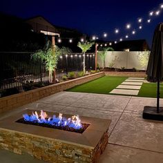 an outdoor fire pit in the middle of a yard with lights on it and grass