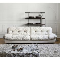 a white couch sitting on top of a wooden floor next to a book shelf filled with books