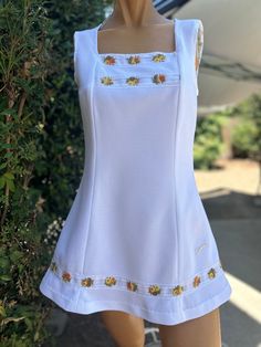 Here is a vintage 1970s Slazenger tennis dress.No size.Following are the measurements.Bust 34",Waist 32",Hips full,Length measured from top of shoulder to hem 30"long.Zips up the back.Made out of a white polyester fabric.Peach & yellow colored flowers trim around bodice and hem.Nice vintage condition.Please take special consideration of measurements. 1970s sizing was much smaller than today's standards.Tennis dresses were very short not like a regular dress. So please take special note of length Vintage Tennis Dress, Tennis Dresses, 1900 Fashion, Tennis Outfit Women, Tennis Bag, Vintage Tennis, Tennis Fashion, Womens Sports, Colored Flowers