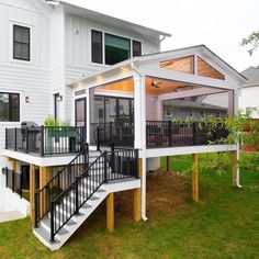 a white house with black balconies on the front porch and stairs leading up to it