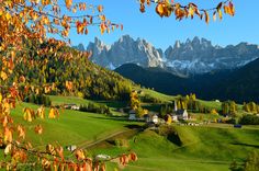 the mountains are covered with green grass and trees, while houses stand in the foreground