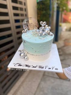 a blue and white cake sitting on top of a paper plate with silver decorations around it