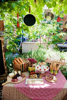 an outdoor table with food and utensils set up for a party or gathering