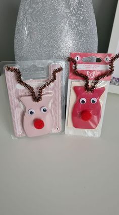 two bags with reindeer faces on them sitting next to each other in front of a silver vase