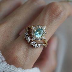 a close up of a person's hand wearing a ring with an aqua stone