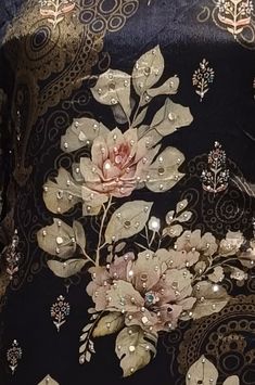 a close up of a black and gold dress with flowers on it