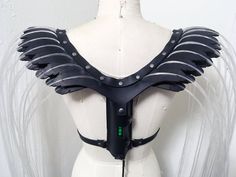 a white mannequin with black leather wings on it's chest and back