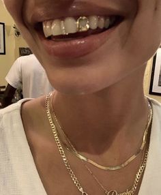 a smiling woman wearing gold chains and a white shirt