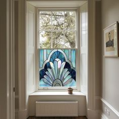 a stained glass window in the corner of a room with wood flooring and white walls